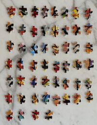 Overhead image of a grid of jigsaw puzzle pieces on a white marble background.