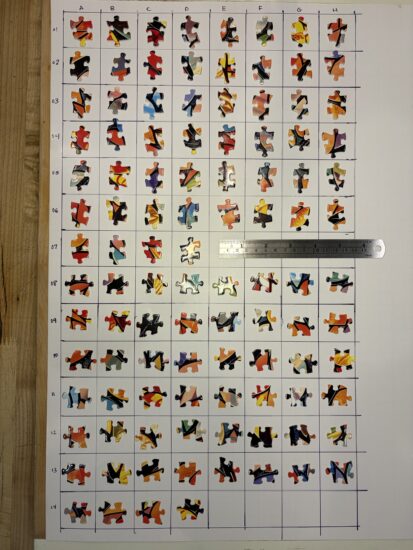 Overhead photo of jigsaw puzzle pieces aligned on a grid with letters denoting columns and numbers for rows